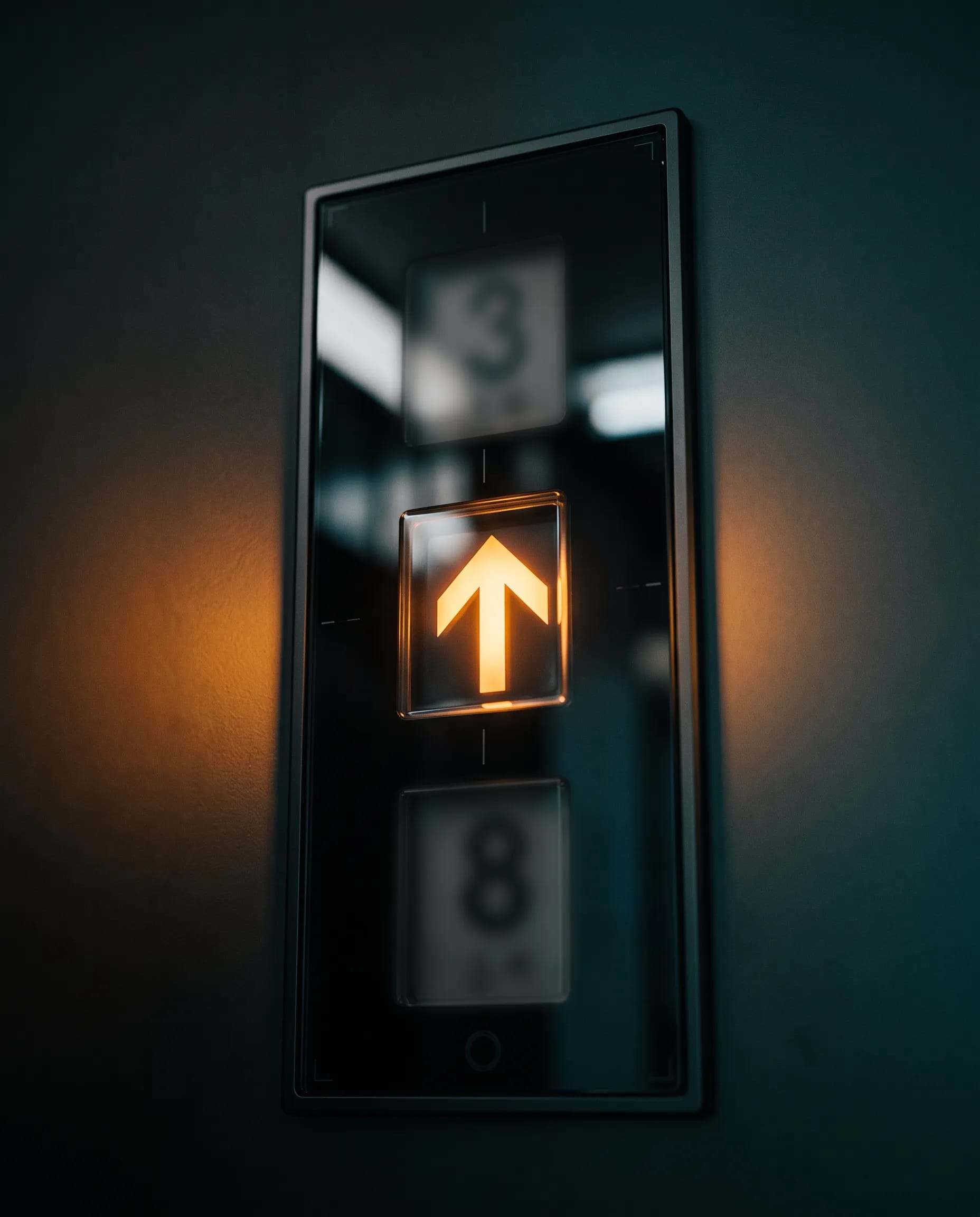A lift's floor indicator arrow pointing upwards in warm light